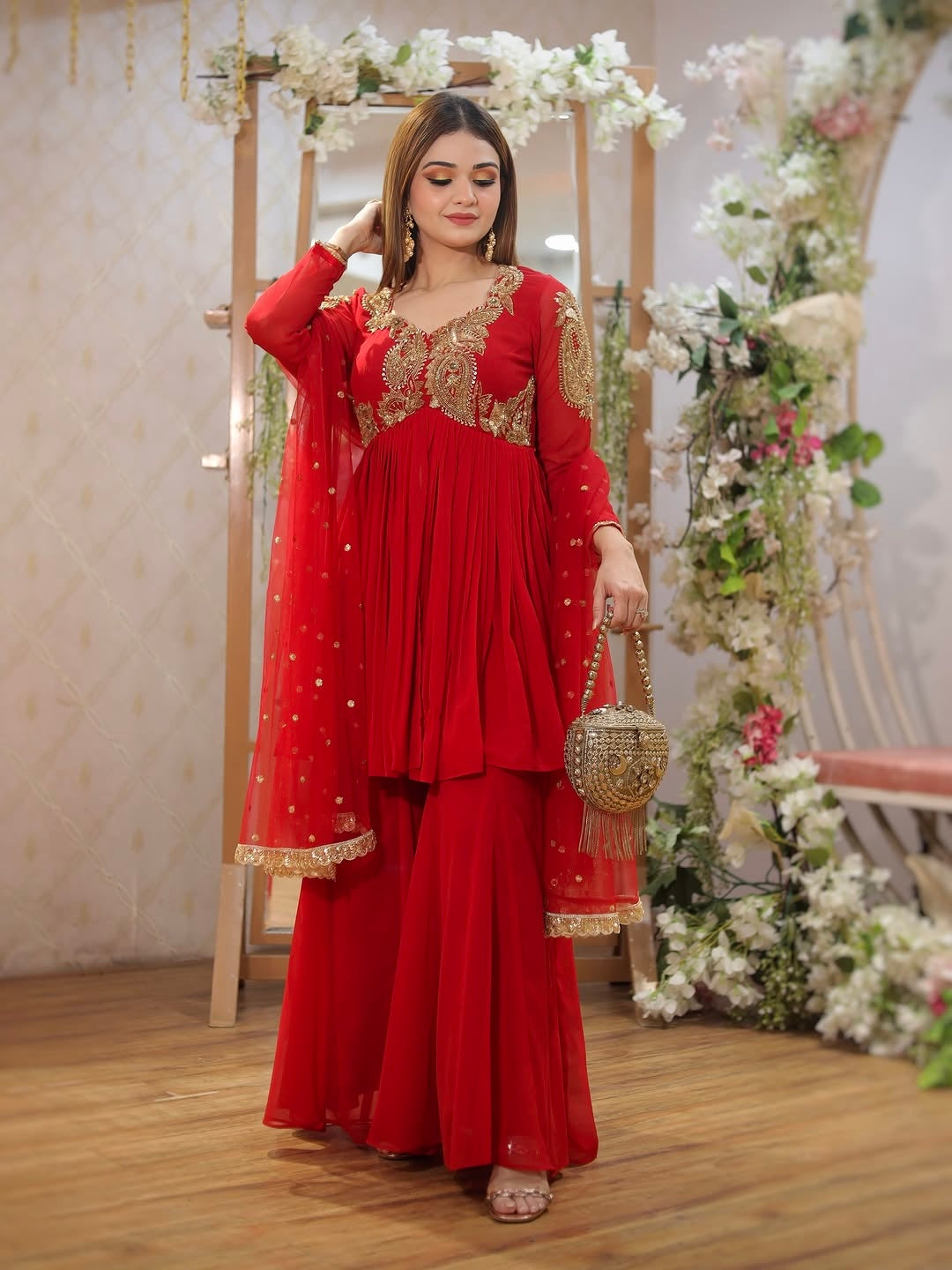 Designer Traditional Red Anarkali Floor-Length Gown with Heavy Golden Zari Embroidery on Bodice and Sleeves, Paired with Golden Beaded Potli Bag and Statement Jewelry – Ideal for Wedding, Festive, or Party Wear