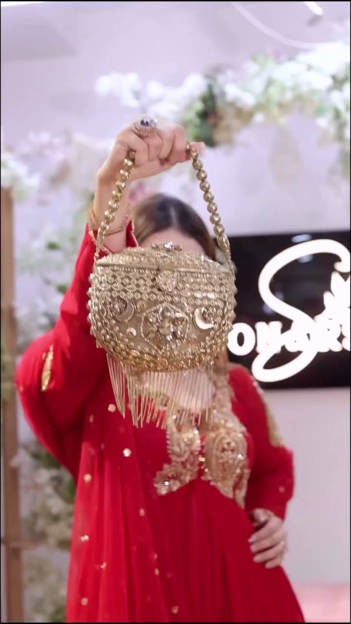 Designer Traditional Red Anarkali Floor-Length Gown with Heavy Golden Zari Embroidery on Bodice and Sleeves, Paired with Golden Beaded Potli Bag and Statement Jewelry – Ideal for Wedding, Festive, or Party Wear